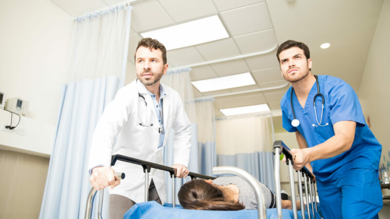 Couple of doctors using a gurney to transport a female patient to an operating room during an emergency